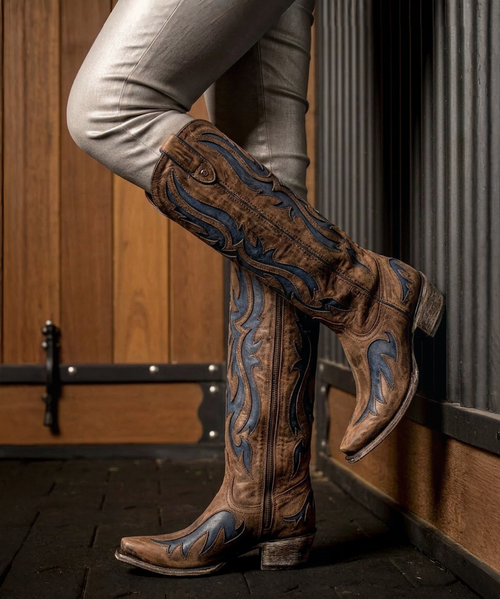 The Clint Boot by El Vaquero is a striking over-the-knee silhouette that blends refined craftsmanship with effortless summer elegance. Distinguished by a sleek ankle strap and beautifully detailed leather accents along the shaft, this boot delivers unmistakable style with a soft, artisanal feel.

Crafted in Italy from a unique combination of luxurious calfskin suede and fine natural linen, Clint offers a fresh, lightweight construction that’s perfect for warm-weather styling. The subtle 7 cm internal wedge provides comfortable lift without compromising ease, while the vintage treatment adds character and depth to every pair.

Finished with handcrafted stitching, nickel-free metal details, and a durable rubber sole, the Clint boot is designed for confident, all-day wear. Elegant yet relaxed, it pairs effortlessly with flowy dresses, tailored shorts, or layered summer looks.

Details:

Over-the-knee boot

Internal wedge: 7 cm

Vintage treatment

100% calfskin suede and natural linen

Handcrafted stitching

Nickel-free metal details

Rubber sole

Made in Italy