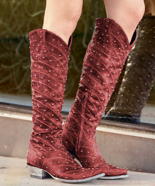 Make a statement in every step with these bold, handcrafted western boots—where classic cowgirl style meets elevated, artisan detail.

Crafted from premium black leather, these boots feature intricate contrast stitching in a feather-inspired pattern that flows across the shaft and vamp, delivering timeless western character with a refined edge. The sleek pointed toe and angled heel create a flattering, feminine silhouette that’s both versatile and striking.

What truly sets this pair apart is the ornate vertical overlay panel, adorned with hand-set metal studs and rich red stone accents. A signature Double D Ranch medallion charm drapes elegantly from the panel, adding movement and a collectible, heritage-inspired touch.

At the back, a contrasting textured leather heel counter with a spotted, exotic finish brings unexpected dimension and standout style. A side zipper ensures easy on-and-off without compromising the clean, classic profile.

Perfect for pairing with dresses, denim, or statement looks, these boots embody western tradition with a bold, fashion-forward spirit.

Details:

Premium black leather construction

Intricate contrast western stitching

Studded overlay with red stone embellishments

Signature medallion charm detail

Textured heel counter for added contrast

Side zipper closure

Pointed toe & stacked heel

Confident. Detailed. Unmistakably cowgirl.