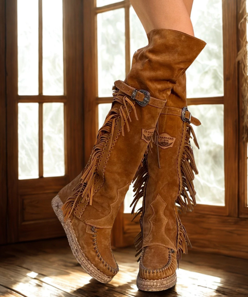 Coleen allows you to explore the world without worrying.  Its combination of prime quality calf leather and vegetable tanned cowhide guarantees maximum comfort.  Our vintage treatment, together with hand-stitched raw laces, give this boot a unique touch complemented by indomitable fringes and an elegant side buckle. In Mou color.