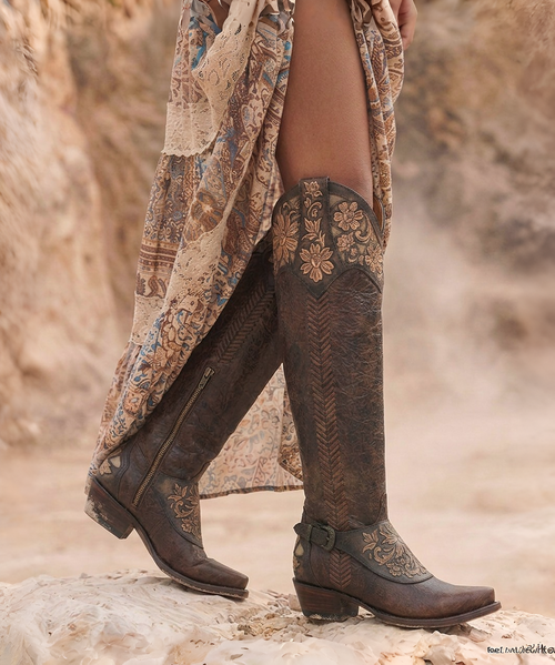 ## Old Gringo Aster Brass Hand-Tooled Tall Western Boot

Bold, elegant, and unmistakably Old Gringo, the **Aster Brass** is a stunning showcase of artisan craftsmanship. Rich brass leather is beautifully contrasted with hand-tooled tan leather overlays featuring intricate floral patterns, creating a timeless Western design with exceptional depth and character. Every detail is carefully handcrafted, making this boot a true statement piece that will turn heads wherever you go.

The dramatic **18-inch knee-high shaft** offers a flattering silhouette, while the signature **Sintino heel** and **Sintino-4 toe** provide a refined Western profile that's both stylish and comfortable. Whether paired with your favorite skinny jeans, a flowing dress, or layered with boho-inspired pieces, the Aster Brass effortlessly transitions from everyday wear to special occasions.

Handcrafted in Mexico using premium leathers and traditional techniques, each pair reflects the quality and individuality that has made Old Gringo one of the most sought-after names in luxury Western footwear.

### Details

* Handcrafted in Mexico
* Premium brass leather construction
* Hand-tooled tan leather overlays with floral detailing
* Intricate artisan tooling throughout
* Decorative buckle harness accents
* Approximately 18-inch shaft height
* Sintino heel
* Sintino-4 toe
* Leather outsole
* Signature Old Gringo craftsmanship

**Please Note:** Every pair of Old Gringo boots is individually handcrafted using premium natural leathers. Variations in color, tooling, leather grain, distressing, and hand-finishing are part of the authentic character of each pair, ensuring every pair is truly one of a kind.
