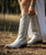 The Clint Boot by El Vaquero is a striking over-the-knee silhouette that blends refined craftsmanship with effortless summer elegance. Distinguished by a sleek ankle strap and beautifully detailed leather accents along the shaft, this boot delivers unmistakable style with a soft, artisanal feel.

Crafted in Italy from a unique combination of luxurious calfskin suede and fine natural linen, Clint offers a fresh, lightweight construction that’s perfect for warm-weather styling. The subtle 7 cm internal wedge provides comfortable lift without compromising ease, while the vintage treatment adds character and depth to every pair.

Finished with handcrafted stitching, nickel-free metal details, and a durable rubber sole, the Clint boot is designed for confident, all-day wear. Elegant yet relaxed, it pairs effortlessly with flowy dresses, tailored shorts, or layered summer looks.

Details:

Over-the-knee boot

Internal wedge: 7 cm

Vintage treatment

100% calfskin suede and natural linen

Handcrafted stitching

Nickel-free metal details

Rubber sole

Made in Italy