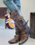 The Frontier Trapper Boot  has a rustic look with  the wear-and-tear holes and patching, which comes from a combination of 5 worn and perfectly distressed leather. The side-pocket and the bullet keeper on the back were an afterthought to the original design. Perfect for the modern-day "trapper gal" to store her cell phone, credit cards, and a little ammo.  Load'em up and get going!
Snip Toe
Cowgirl Heel
16" Shaft including heel
2" Heel
Distressed Leather
Metal Stud Embellishment
 