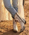 These boots are a striking blend of vintage Western tradition and Americana-inspired artistry. With their weathered finish, handcrafted details, and iconic lucky symbols, they feel like a pair that has been collected over decades and passed down with stories to tell.

Product Description

Channel timeless Western heritage with these statement-making handcrafted boots that celebrate luck, freedom, and authentic cowboy style. Crafted from beautifully distressed crackled ivory leather, they feature a perfectly broken-in vintage finish that gives each pair incredible character from the very first wear.

The tall shaft is adorned with layered leather appliqués, whipstitched trim, antique nailhead studs, and intricate embroidery that create remarkable depth and texture. At the center of the design, a classic horseshoe and Western star symbolize good fortune and adventure, while sweeping gray leather inlays add movement inspired by traditional cowboy scrollwork.

The soft gray distressed toe and heel counters create a beautiful contrast against the creamy white leather, enhancing the boot's rustic appeal. Antique-inspired studding outlines every panel, giving the design an heirloom quality reminiscent of vintage rodeo boots and collectible Western pieces.

A square snip toe, leather sole, and stacked cowboy heel complete the silhouette with comfort and timeless style, while the hand-finished distressed leather ensures no two pairs are exactly alike.