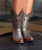 Meet your next go-to pair — a stunning blend of rugged charm and refined Western attitude. This style features a rich Mineral Grey and Tobacco Brown colorway, creating a bold, earthy contrast that’s as versatile as it is striking.

Crafted from premium cowhide leather, these boots deliver durability with a smooth, elevated finish. The 4Long toe adds sleek Western length, while the 9964 heel provides that perfect, easy-riding lift. At 11" tall, this silhouette is the ideal mid-height boot — effortless to style with denim, dresses, or everyday looks.

A timeless Western essential with modern edge, ready to turn heads wherever you roam.

Details:

Color: Mineral Grey / Tobacco Brown

Leather: Cowhide

Toe: 4Long

Heel: 9964

Height: 11"