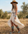This image captures a striking **modern boho-western look** with a blend of romantic femininity and rugged Southwestern style.

### Outfit Description

The model is wearing a **black silk slip dress** with delicate **black lace trim** along the neckline and asymmetrical hem. The dress features a flowing high-low silhouette that moves beautifully and gives it an effortless, free-spirited feel.

Layered around the waist is a **wide vintage-style concho belt** with oversized silver conchos, adding a classic Southwestern touch and defining the waist.

She pairs the dress with **black mid-calf western boots** featuring:

* Fringe detailing along the shaft
* Decorative ankle straps with tassels
* A slightly distressed suede or nubuck finish
* A low western heel
* A pointed toe

Her accessories complete the bohemian aesthetic with multiple **stacked sterling silver and turquoise cuffs and bracelets**, along with turquoise rings that add color and authentic Western character.

A **wide-brim black felt rancher hat** frames her long, tousled blonde hair, giving the look a relaxed yet sophisticated finish.

### Styling Aesthetic

This outfit perfectly blends:

* ? Modern Western
* ? Desert Bohemian
* ✨ Festival Luxe
* ? Romantic Gothic Western
* ? Free-Spirited Cowgirl

It's reminiscent of styling from brands like:

* Chasing Unicorns
* El Vaquero
* Old Gringo
* Double D Ranch
* Magnolia Pearl

### Setting

The model is photographed in a **desert landscape** with red sand, dry grasses, and scattered trees beneath a soft blue sky. The natural backdrop complements the earthy, Southwestern mood of the outfit and reinforces its adventurous, wanderlust-inspired feel.

### Product Description

**Take the Long Road Home Silk Lace Slip Dress – Black**

Gracefully feminine with a touch of Western soul, this flowing black silk slip dress is designed for the woman who loves effortless elegance. Delicate lace accents frame the neckline and cascading high-low hem, creating beautiful movement with every step. Styled with a vintage concho belt, turquoise jewelry, and statement cowboy boots, it's the perfect piece for everything from concerts and festivals to date nights and special occasions.

Whether you're strolling through the desert, dancing under the stars, or heading out for an evening downtown, this timeless dress captures the essence of modern boho luxury—romantic, confident, and undeniably unforgettable. ??

