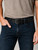 A man wearing dark blue denim pants, a brown t-shirt, and a full grain triple prong leather belt.