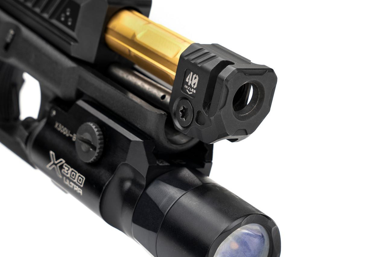 Strike Industries SI-MC-QUAD Micro Threaded Barrel Comp - QUAD, a black firearm accessory with a threaded exterior and a small opening for firearm compatibility, mounted on a gun with a tactical scope.