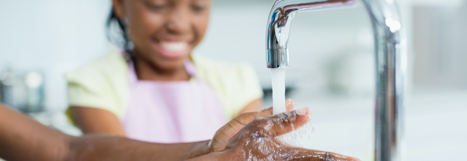 two young children washing hands in kitchen faucet