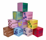 A pyramid display of ten Heaven Scent 20cl Modern Botanical vegan soy candles in boxes, featuring bright colour-pop designs to match aromas including Black Cherry, Black Opium and more