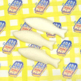 A box of Sea Salt & Spray scented wax melts in the shape of sardines, shown both inside their illustrated gift box and resting beside it. The FSC-certified packaging features a whimsical illustration by Sarah Pettitt of a sardine tin on a pink and white chequered background.