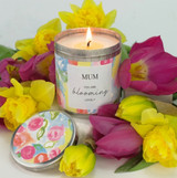 Heaven Scent's limited edition Mother's Day candle with a floral label stating, 'Mum You're Blooming Lovely', surrounded by yellow daffodils and dark pink tulips