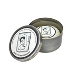 Heaven Scent natural vegan shaving soap bar wrapped in glassine paper inside an open, brushed metal travel tin featuring a black and white illustrated woman shaving, scented with Black Pomegranate.