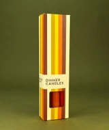 A beautifully illustrated, autumn-striped gift box for Heaven Scent's The Autumn Edit mixed dinner candles, displayed alongside six straight, hand-poured artisan dinner candles in complementary shades of Pumpkin Orange, Dark Brown and Burnt Orange.