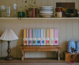 A beautifully illustrated, cream and yellow striped gift box for Heaven Scent's The Natural Edit dinner candles, displayed alongside six straight, hand-poured artisan dinner candles in a classic, solid Natural shade, along