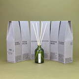A 100ml luxury Winter Moss Green Botanical reed diffuser by Heaven Scent, housed in an elegant green apothecary glass bottle with natural rattan reeds, made in the UK.