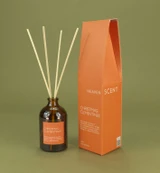 Christmas Clementines 100ml amber apothecary glass Christmas reed diffuser from the Modern Heritage collection, shown with natural rattan reeds and its bright orange gift box.
