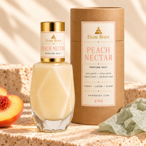 Peach Nectar Perfume Mist in a faceted glass bottle with gold cap and matching cream-and-gold labeled kraft tube, with peach and sage tissue on warm travertine.