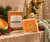 Hers + His Too Soap Bar with African net sponge on a wet ivory shower ledge with fresh evergreen and citrus botanicals