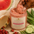 Close-up of Dame Body Watermelon Polishing Body Scrub as a Black hand scoops the thick pink exfoliating texture from the open jar.