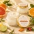 Open Citrus + Agave Body Butter showing its rich ivory texture beside the approved orange-and-gold lid label.