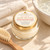 Baby Body Butter with its approved peach pink label beside a folded ivory towel, bath basin and wooden brush for the gentle moisture ritual.