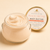 Open Peach Nectar Body Butter showing its creamy texture beside the peach-accented gold lid