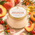 Peach Nectar Body Butter with its peach-and-gold Dame Body label among peaches, apricots, rosehip, sea buckthorn and golden oil in warm botanical light.