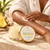 Black woman gently smoothing Pineapple Ginger Body Butter onto her forearm beside the current-label jar.