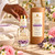 Hand reaching for Jasmine Rose Perfume with amethyst chips beside body butter and a cream towel for an after-shower ritual.