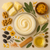 Botanical flat lay with open ivory body butter, butter pieces, calendula flowers, walnuts, seeds and herbs.