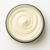Close view of the rich ivory Nourishing Eczema Butter swirl in an open glass jar.