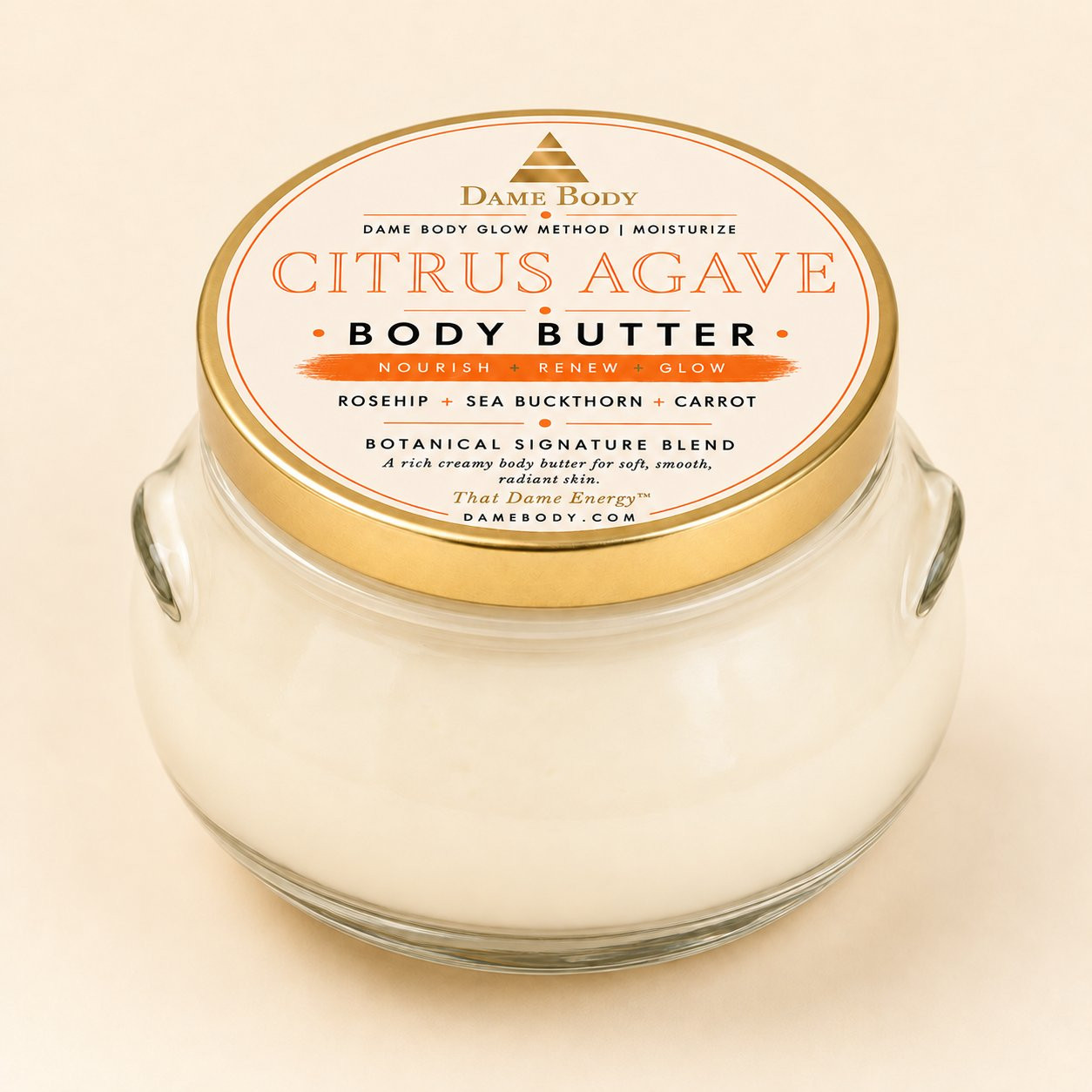 Citrus + Agave Body Butter in a clear glass jar with its current cream, orange and gold Dame Body lid label.