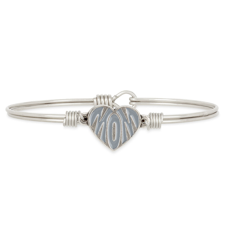 It’s just like Mom to fill our hearts with joy. Wear this handmade bracelet in honor of her, or give it to Mom as a token of your own unconditional love. A unique heart design is filled with her moniker in either a gray or teal glossy finish, styled a classic Luca + Danni setting of silver or gold. 

Handmade using brass and artisan metals
Easy hook and catch closure
Regular or petite sizing options and oval shape ensures proper fit
Silver tone finish
MOM engraved heart charm with gray epoxy

Packaged in a gift box and includes an essence card
Made in the USA