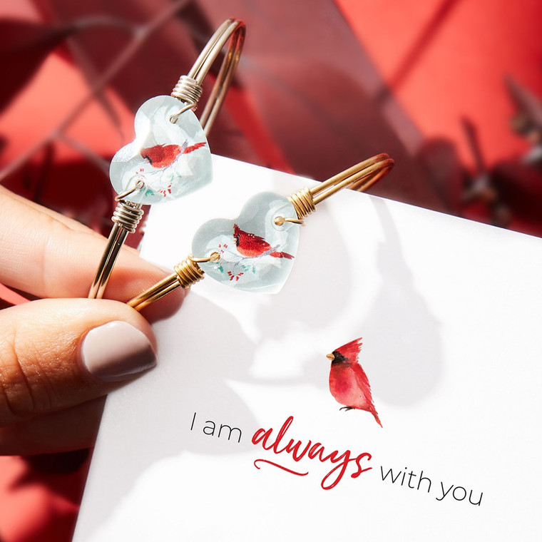 Wear this crystal-clear reminder of the loved ones who still surround you. Our digitally-printed Cardinal Crystal Heart Bangle shines in a heart-shaped Swarovski® crystal design, and is a limited edition piece for the holiday season.

Handmade using brass and artisan metals
Easy hook and catch closure
Oval shape ensures proper fit
Brass finish
Digitally printed Swarovski® crystal with red cardinal
Includes an essence card
Made in the USA