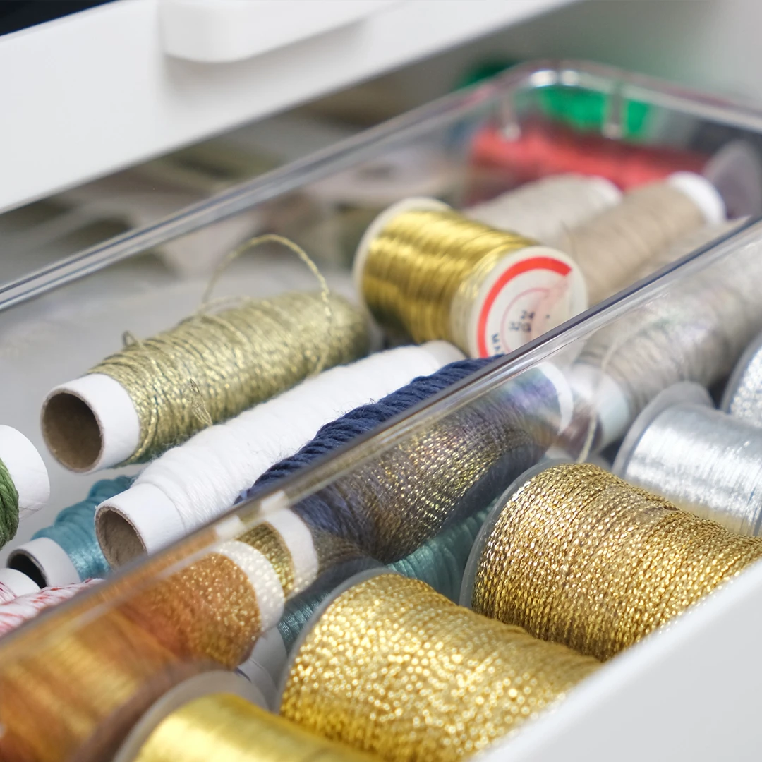 Small ribbon spools and twine stored in Acrylic Drawer Cups inside an open drawer