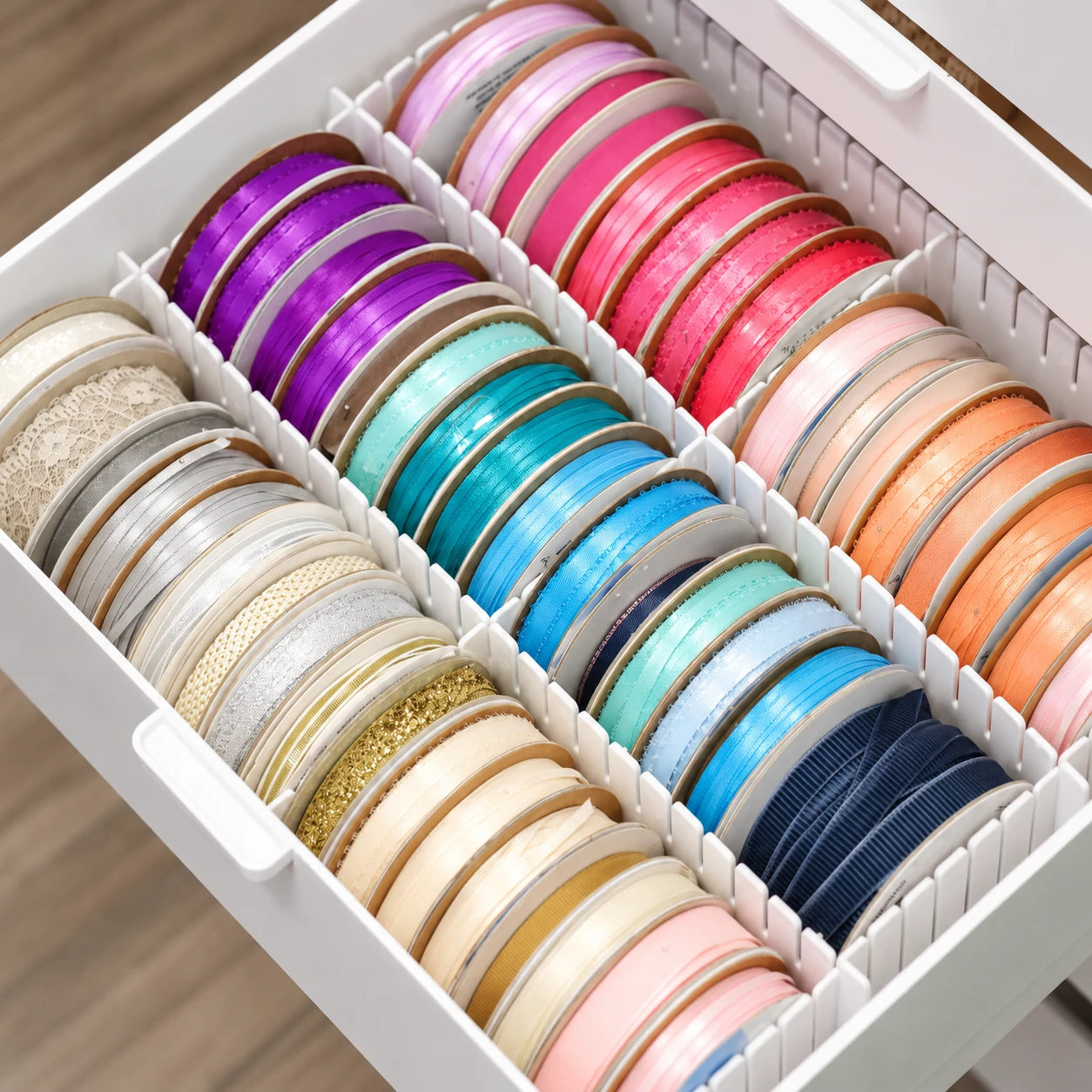 Ribbon spools separated into rows by Flexi Drawer Dividers inside a craft drawer