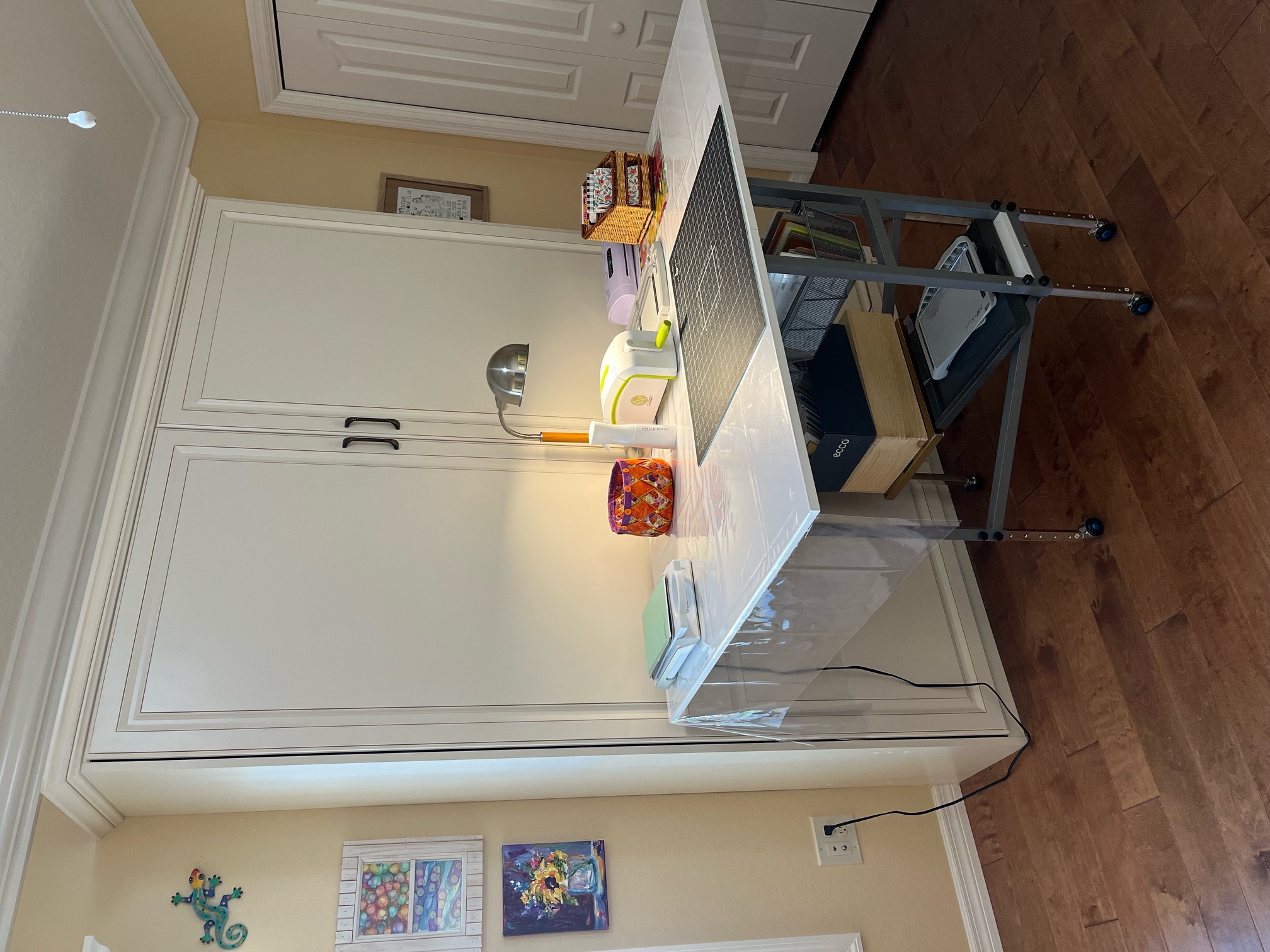 Desk in front of closed murphy bed cabinet doors with work surface and crafting tools