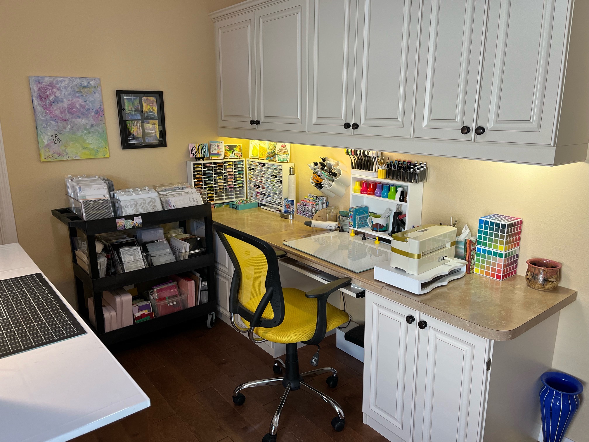 Craft room set up with desk, rolling storage cart, and card-making supplies