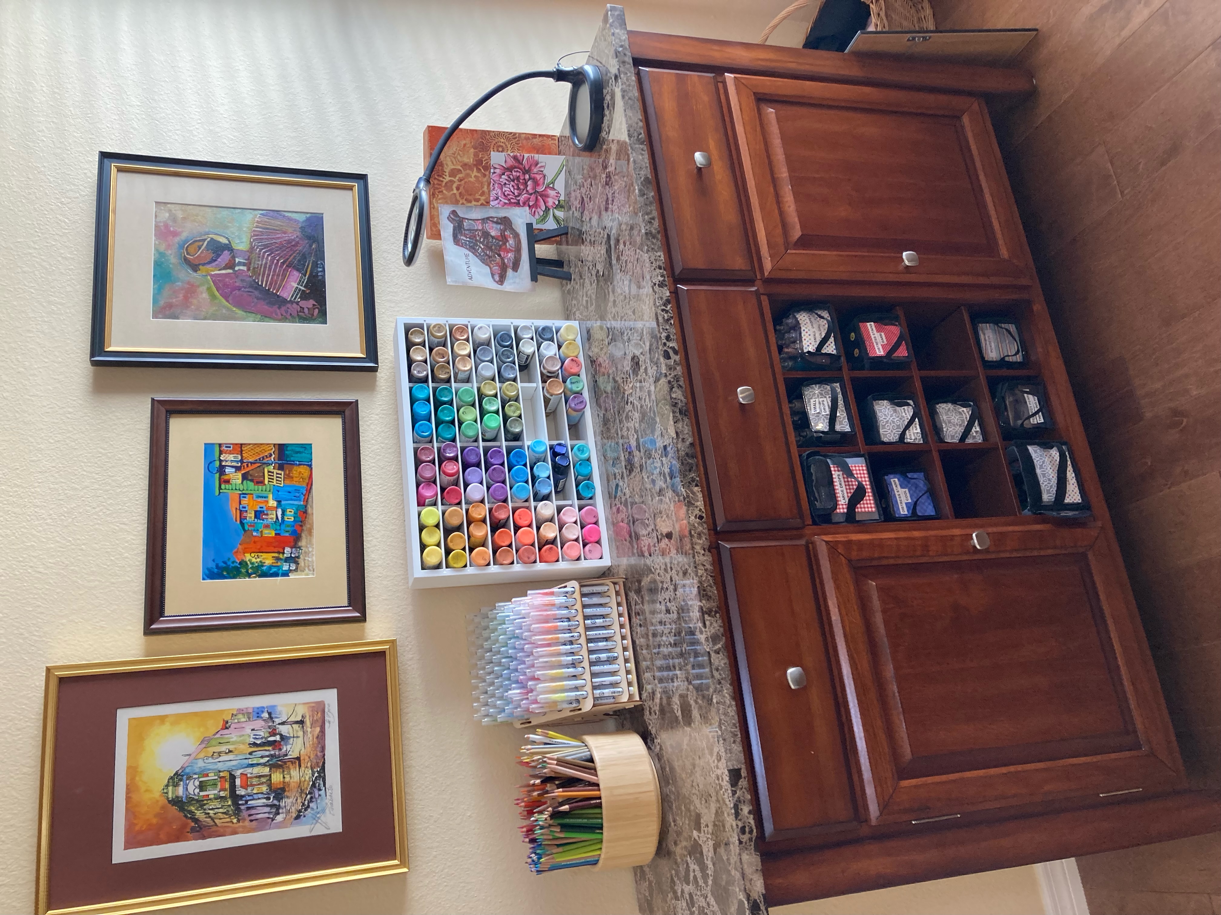 Wall with paintings, paints, markers, colored pencils, a cabinet with countertop and storage compartments
