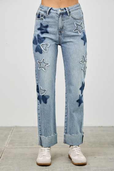 "Light wash high-waisted straight-leg jeans featuring dark denim heart and star patchwork appliqués with raw-edge cuffed hems."