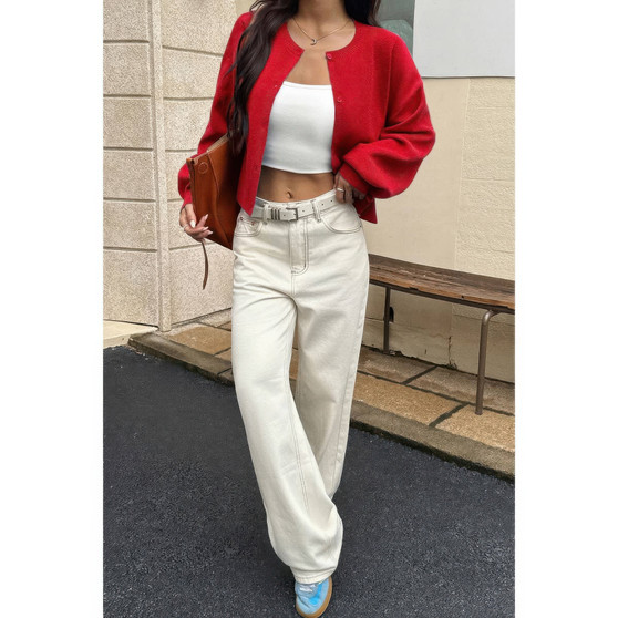 Woman wearing a cropped red cardigan with balloon sleeves and off-white wide-leg jeans.