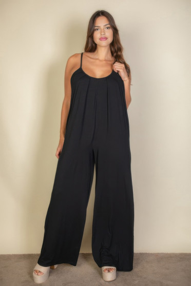 A woman wearing a relaxed-fit jumpsuit with thin spaghetti straps and a wide-leg silhouette.