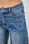 Detail shot of copper metal buttons running down the side seam of flared blue jeans.