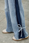 "Front view of wide-leg denim showcasing a dual-wash design: a faded light-blue center with stark dark-blue side panels that create a slimming vertical effect."