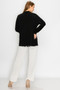 Women's open cardigan layered over a black and white patterned blouse.
