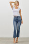 Front view of a person wearing high-waisted, medium-wash denim jeans. The jeans have two horizontal zipper accents below the waistband, a cropped length, and metal zippers on the outer side of each ankle. The model is wearing transparent strap heels.