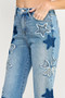 "Detailed shot of dark wash denim heart and star patches on light blue cuffed jeans."