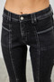 "Close-up of high-rise straight-leg jeans in a charcoal wash, featuring horizontal patch pocket seams and distinct vertical piping down the front of the legs."
