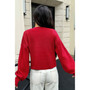 Modern street style outfit featuring a red cropped knit top, white leather belt, and wide-leg trousers.