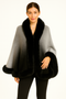 Woman wearing a grey and black ombré shawl cape with plush black faux fur trim on the collar and hem.